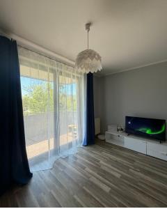 a living room with a television and a large window at Apartament Marco z balkonem in Oleśnica