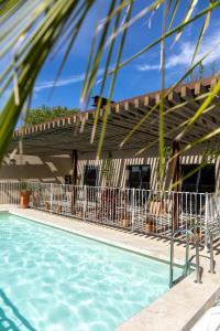 a view of a swimming pool with a house at Hôtel les jardins du canal - piscine chauffée - solaire eco responsable - parking - garage - bornes électriques - accueil vélos - kids friendly in Aigues-Mortes
