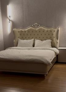 a white bed with a large headboard and white pillows at Grape Resort منتجع وشاليهات عنب in Ajloun