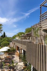 an external view of a house with a wooden fence at Hôtel les jardins du canal - piscine chauffée - solaire eco responsable - parking - garage - bornes électriques - accueil vélos - kids friendly in Aigues-Mortes