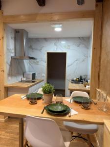 a kitchen with a wooden table and white chairs at A Taberniña in O Pedrouzo +10 photos
