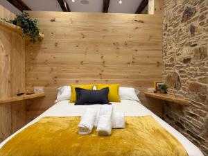 a bedroom with a large bed with yellow and gray pillows at A Taberniña in O Pedrouzo