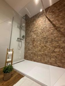a bathroom with a shower with a stone wall at A Taberniña in O Pedrouzo