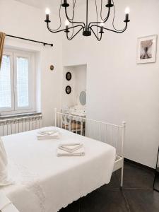 a white bedroom with a bed and a chandelier at Royal Nest Venaria Reale in Venaria Reale