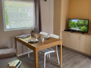 a living room with a wooden table and a television at Aloha Camping Club in Reynès