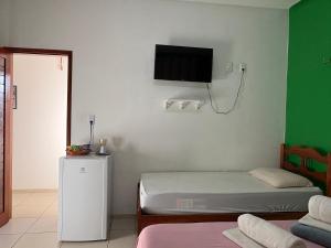a room with two beds and a tv on the wall at Ruta Del Sol in Mossoró