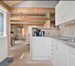 a kitchen with white cabinets and wooden walls at Feriehus Kornblomst in Tversted