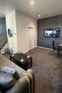 a living room with a couch and a tv on a wall at Central 2 Bed House in Huddersfield