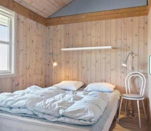 a bed in a room with a wooden wall at Feriehus Kornblomst in Tversted