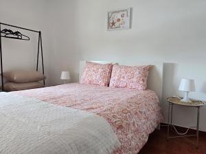 a bedroom with a bed with pink and white sheets and pillows at JB House in Peniche