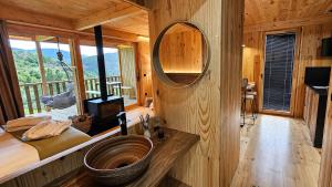 a bathroom with a wooden wall with a large mirror at Cabanas do Navia in Coea