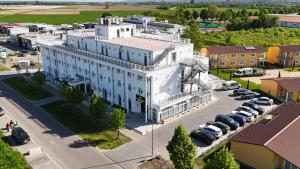 a large white building with cars parked in a parking lot at Hotel Babylon Royal in Ringsheim