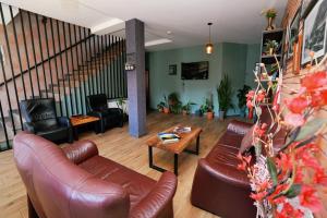 a living room with leather furniture and a staircase at Hilltop Kazbegi in Kazbegi