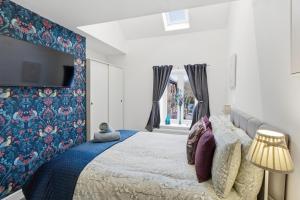 a bedroom with a large bed with a blue wall at Cannons Loft Central Buxton, Duplex loft 3 bedroom Set over 3 floors stairs no lift sleeps 5 in Buxton