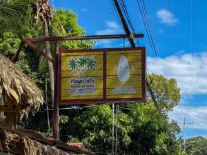 ein Schild für einen Surfshop mit einem Surfbrett darauf in der Unterkunft Playa 506 Beachfront Hostel in Puerto Viejo