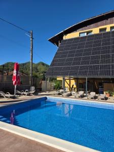 a swimming pool with solar panels on a building at Hotel Trei Brazi in Băile Olăneşti