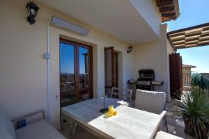 a table and chairs in a room with a balcony at Beautiful Sea and Sunset Views from Apartment CE13, Theseus Village, Aphrodite Hills in Kouklia