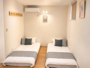 two beds in a room with white walls at 北鎌倉駅徒歩圏 観光便利 最大7名 2寝室 広々滞在 101 in Kamakura