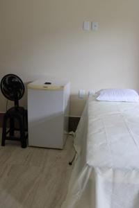 a bedroom with a white bed and a chair at Hotel Club Resort Místico in Coroaci