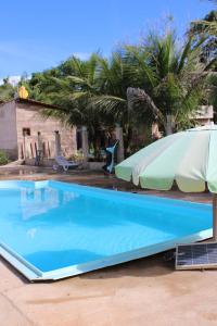 a large blue swimming pool with an umbrella and palm trees at Hotel Club Resort Místico in Coroaci