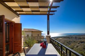 a balcony with a table with red flowers on it at Beautiful Sea and Sunset Views from Apartment CE13, Theseus Village, Aphrodite Hills in Kouklia