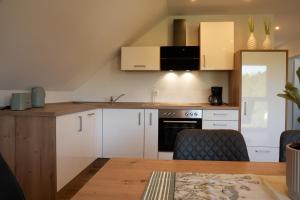 a kitchen with white cabinets and a table with chairs at Ferienwohnung Lindelskopf in Ludwigswinkel