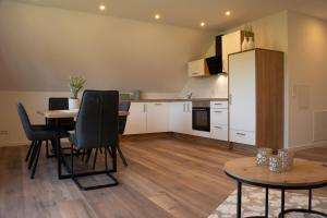 a kitchen with a table and chairs and a refrigerator at Ferienwohnung Lindelskopf in Ludwigswinkel +4 photos