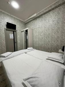 a bedroom with a large white bed in it at Lola Hotel in Yangiyer