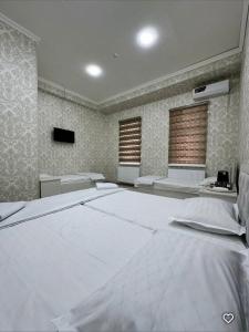 a bedroom with a large bed and two windows at Lola Hotel in Yangiyer