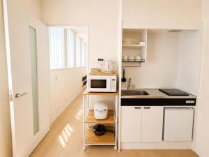 a small kitchen with white cabinets and a microwave at 北鎌倉駅徒歩圏 観光便利 最大7名 2寝室 広々滞在 101 in Kamakura