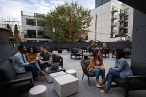 a group of people sitting in chairs on a patio at Dutch Hotel Long Island City New York , Belvilla District 6 Formerly Sonder in Long Island City