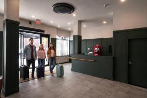 two people with luggage in an airport lobby at Dutch Hotel Long Island City New York , Belvilla District 6 Formerly Sonder in Long Island City
