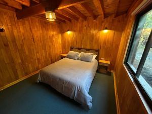a bedroom with a bed in a wooden room at Rayen Mahuida - Las Trancas in Las Trancas