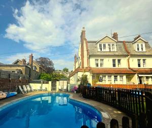 a large swimming pool in front of a house at Yardley Manor Hotel in Torquay
