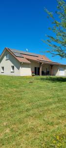a white house with a grass field in front of it at La Maison de choupette in Fougerolles