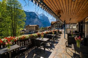 a restaurant with tables and flowers on a balcony at Hotel Restaurant Jungfrau in Lauterbrunnen