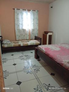 a bedroom with two beds and a tiled floor at Sítio Araújo in Ibiúna