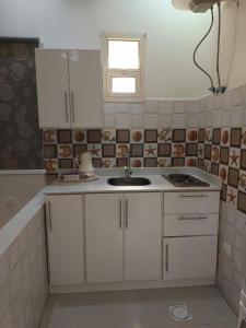 a kitchen with white cabinets and a sink at Quiet Rooms 2 Serviced Apartments in Riyadh