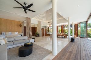 a living room with a couch and a ceiling fan at Private Oceanfront Villa Kingfisher - 20m Infinity Pool in Nusa Lembongan