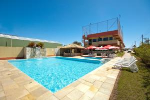 a swimming pool with chairs and umbrellas next to a building at Pousada Vale Del Sol in Bombinhas