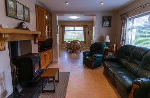 a living room with a leather couch and a tv at Greenway Riverside House - Cahersiveen in Foilmore Bridge