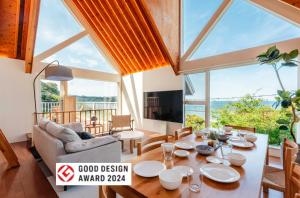 a living room with a table and a couch at 波の音テラス富津ー海眺望グッドデザイン受賞別荘を最大7名1棟貸切 in Futtsu +42 photos