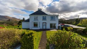 a white house with a black roof at Greenway Riverside House - Cahersiveen in Foilmore Bridge