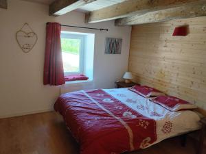 a bedroom with a bed with a red blanket and a window at Maison de charme a moye in Moye