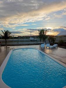 a large blue swimming pool with a sunset in the background at Hotel Village Toritama in Toritama