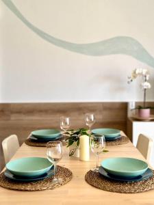 a wooden table with green plates and wine glasses at NextGen Casa Rossy in Antigua