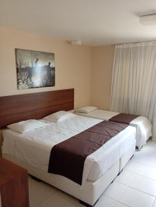 a hotel room with two beds and a picture on the wall at Hotel Village Toritama in Toritama +13 photos
