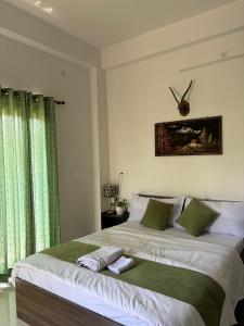 a bedroom with a large bed with green curtains at The Cozy Petals in Gaya