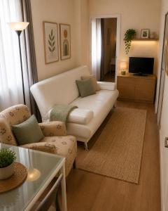 a living room with a white couch and a tv at APARTAMENTOS VIALIA SOL y PLAYA in Málaga