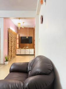 a leather couch in a living room with a television at Richards Shared Apartment-AC in Thiruvalla